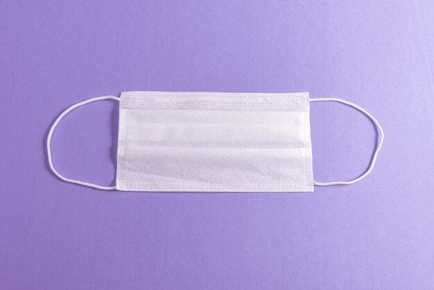 Surgical mask over minimalist purple background