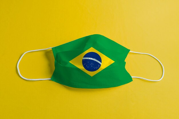 Surgical mask on yellow background with Brazilian flag