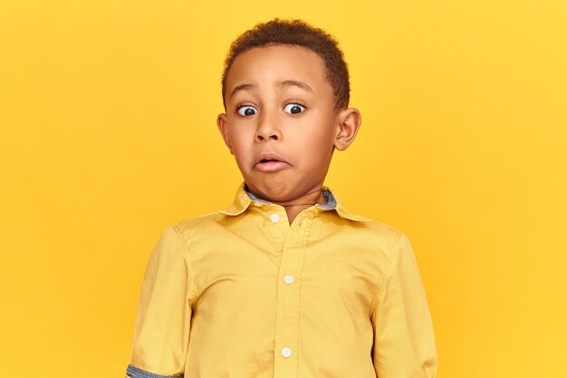 Surprise, astonishment and shock concept. Isolated image of shocked astonished African American little boy expressing true surprised reaction, grimacing while looking at something disgusting