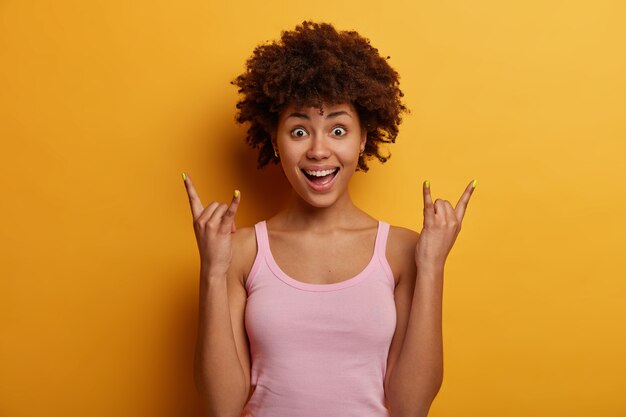 Surprised African American woman makes rock n roll hand sign