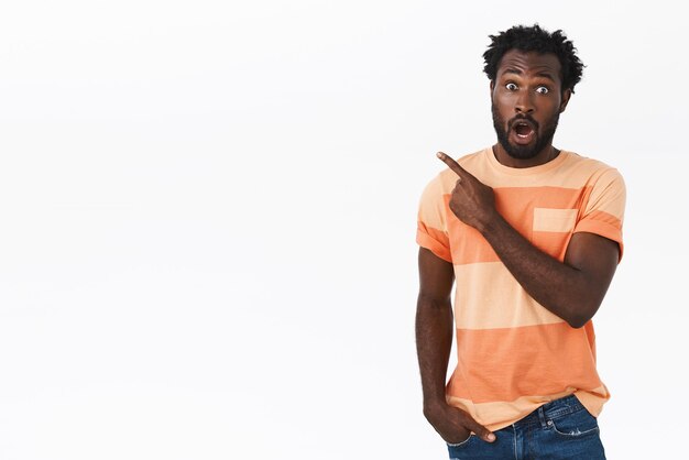 Surprised and amazed attractive young african american man in striped t-shirt, gasping drop jaw from amazement