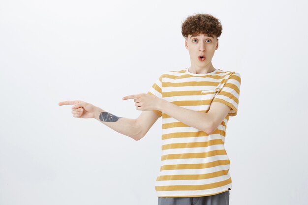 Surprised and amazed teenage guy posing against the white wall