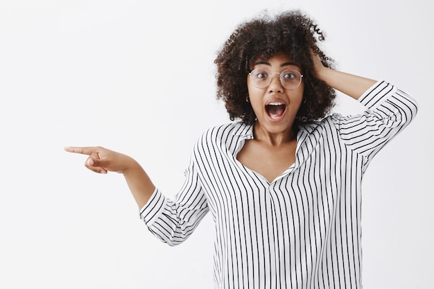 surprised and amazed woman being in shock from unexpected meeting with super star holding hand on hair and pointing left while explaining passionately all details