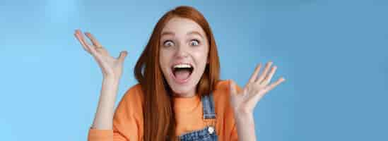 Free photo surprised astonished sensitive overwhelmed young happy redhead girl receive incredible fantastic