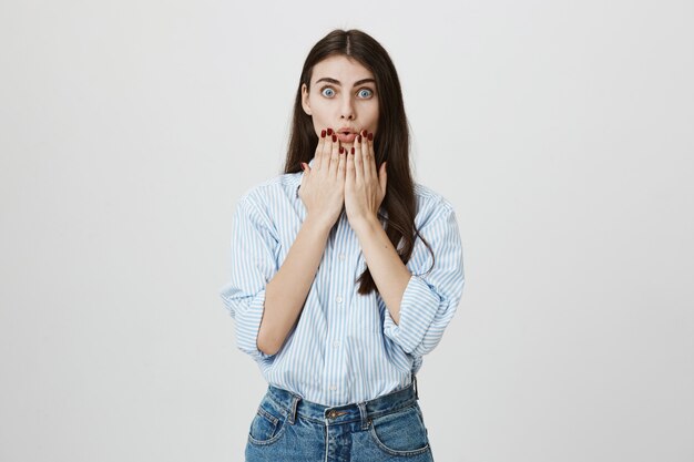 Surprised and astonished woman hold hands on chin