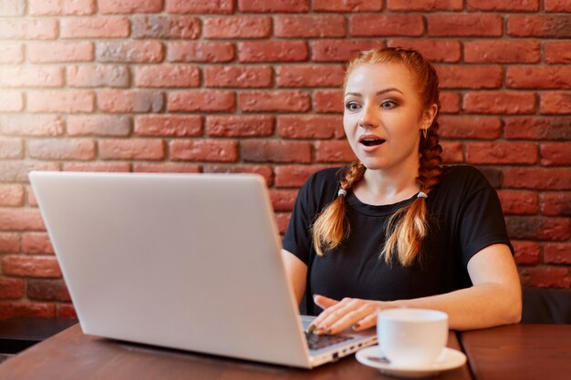 Surprised astonished young woman with red hair and two pigtails