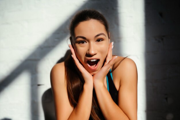 Surprised athletic girl look at camera on the wall background