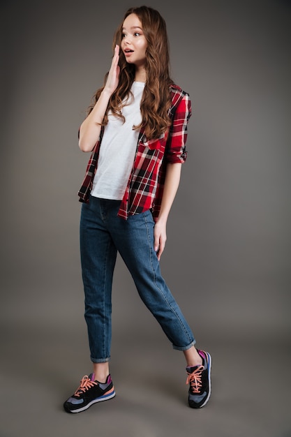 Surprised attractive young woman in plaid shirt and jeans walking