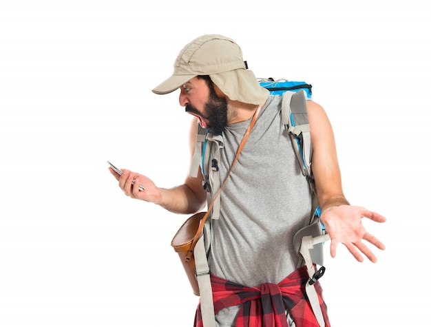 Free photo surprised backpacker talking to mobile over white background