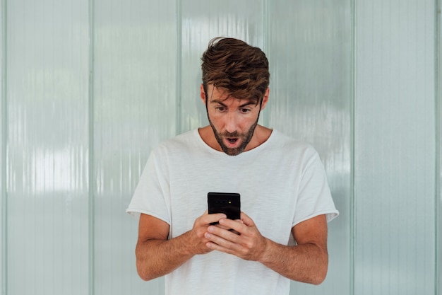 Surprised bearded man with smartphone