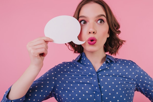 Foto gratuita bella ragazza sorpresa che pensa a qualcosa e distoglie lo sguardo. splendida donna bruna stupita che esprime emozioni sulla parete rosa.