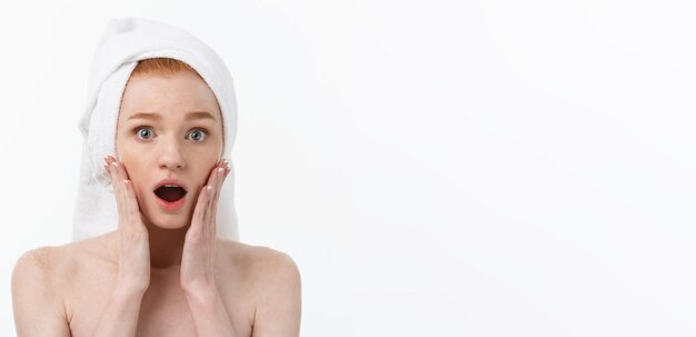 Surprised beautiful young woman after bath with a towel on her head isolated on white background ski