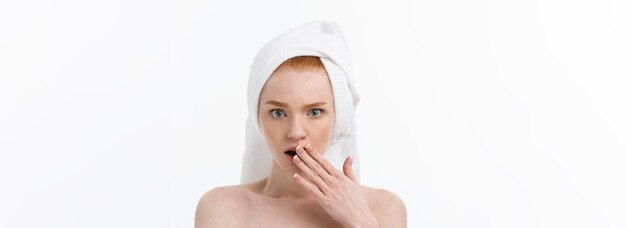 Surprised beautiful young woman after bath with a towel on her head isolated on white background ski