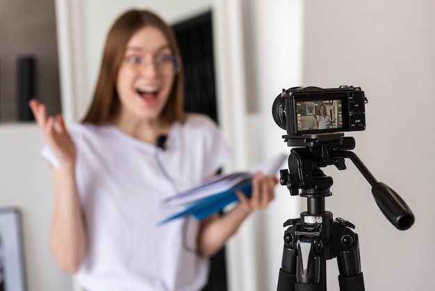 Surprised blogger recording with professional camera holding a book