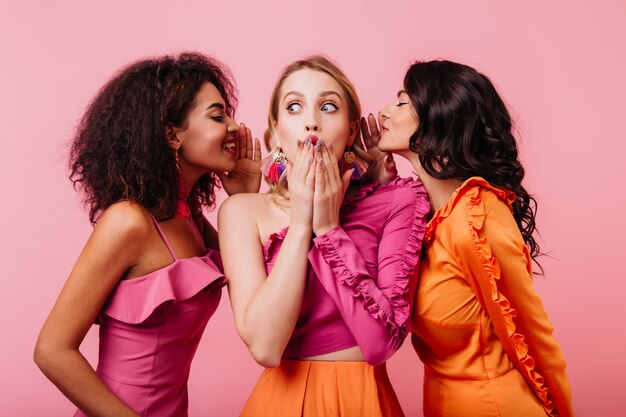 Surprised blonde woman listening friend's secrets