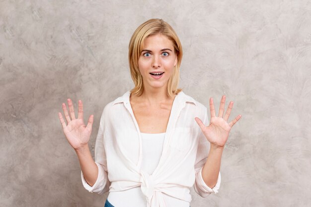 Surprised blonde woman with hands up