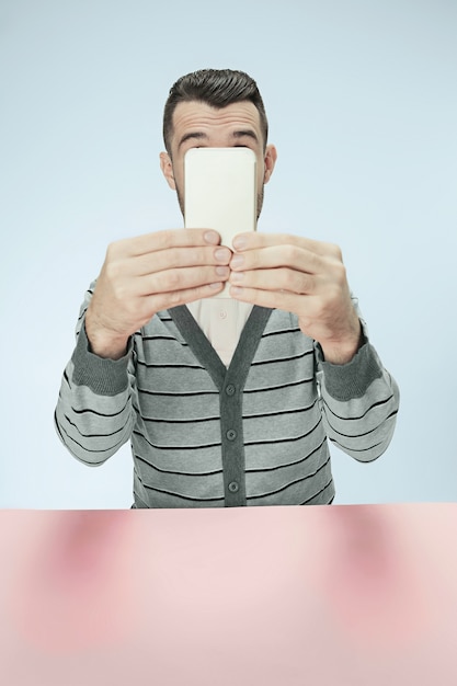 Surprised business man talking on phone sitting at the table.