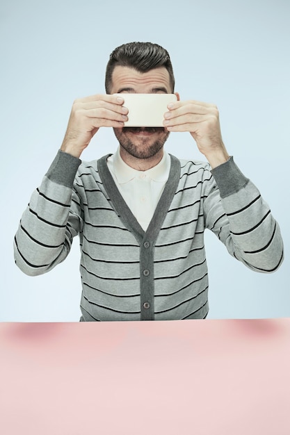 Free photo surprised business man talking on phone sitting at the table.