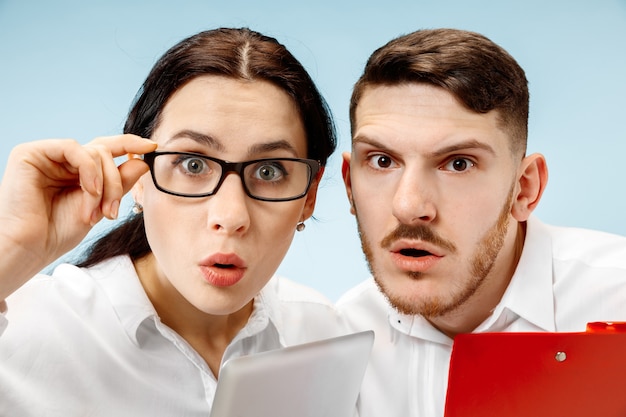 Free photo the surprised business man and woman smiling on a blue studio background