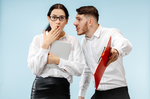 The surprised business man and woman smiling on a blue studio background