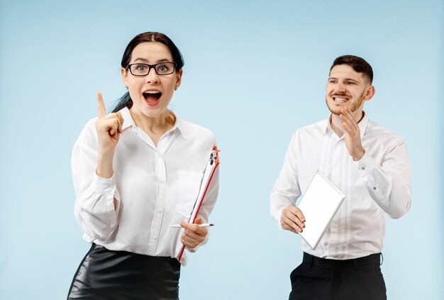 The surprised business man and woman smiling on a blue studio background