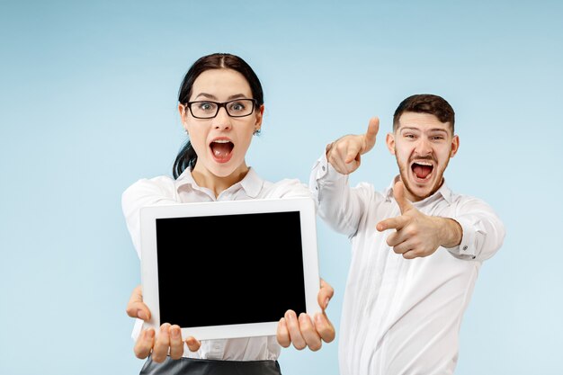 The surprised business man and woman smiling on a blue studio