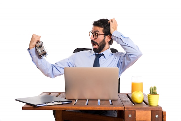 Surprised businessman in his office holding a clock