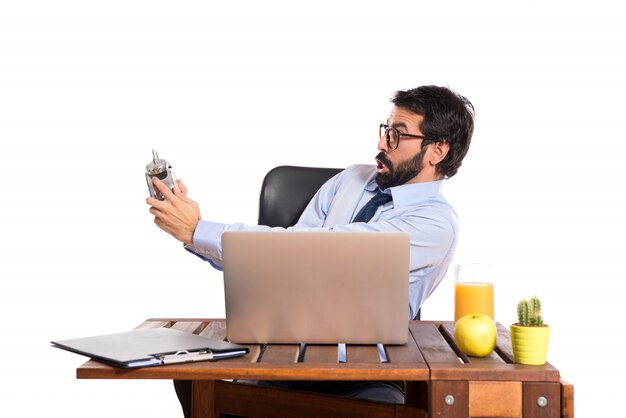 Surprised businessman in his office holding a clock