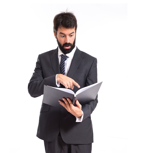 Surprised businessman reading a book over white background