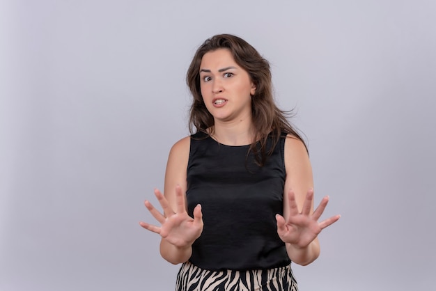 Surprised caucasian young girl wearing black undershirt showing no gesture on white background