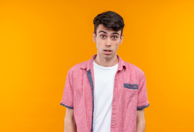 Surprised caucasian young guy wearing pink shirt on isolated orange background