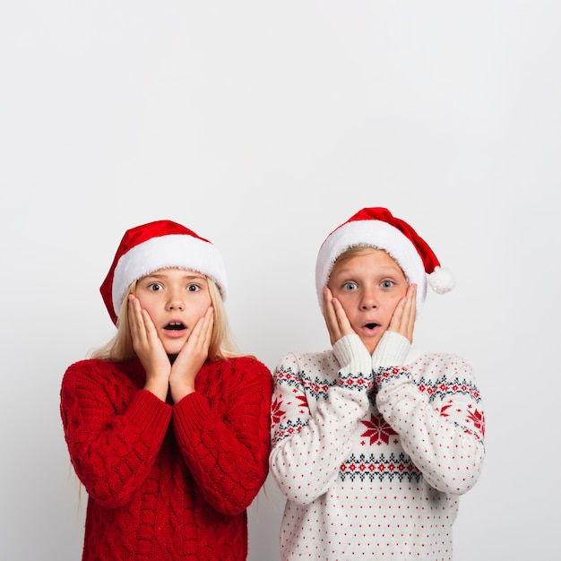 Bambini sorpresi che indossano cappelli di Babbo Natale