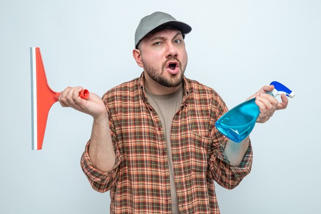 Surprised cleaner man holding squeegee and spray cleaner 