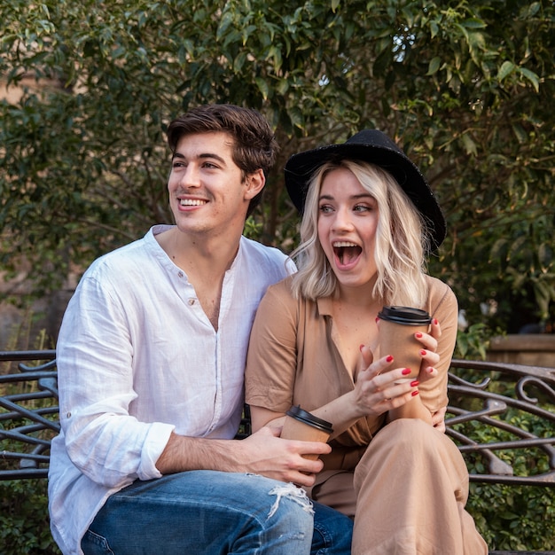 Surprised couple on bench with coffee cup