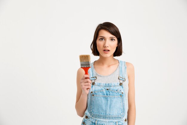 Surprised creative woman with painting brush