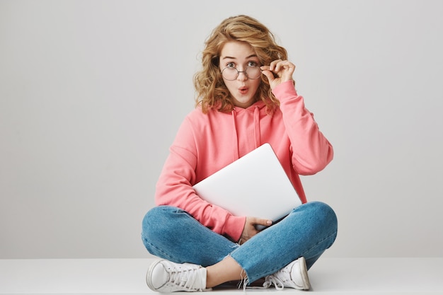 Ragazza dai capelli ricci sorpresa con il portatile, che sembra eccitata