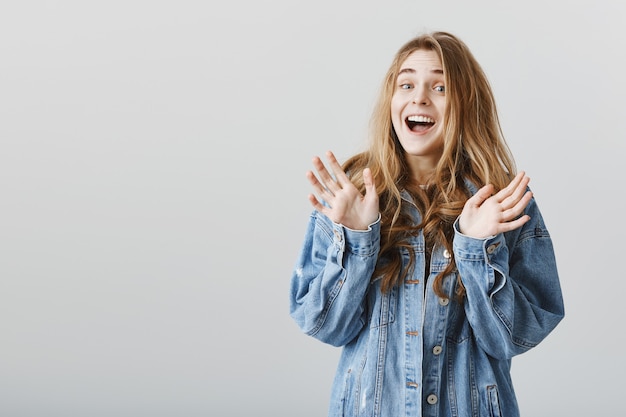 Free photo surprised cute blond girl raising hands up