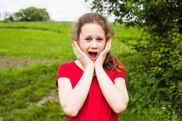 Free photo surprised cute girl standing in beautiful park