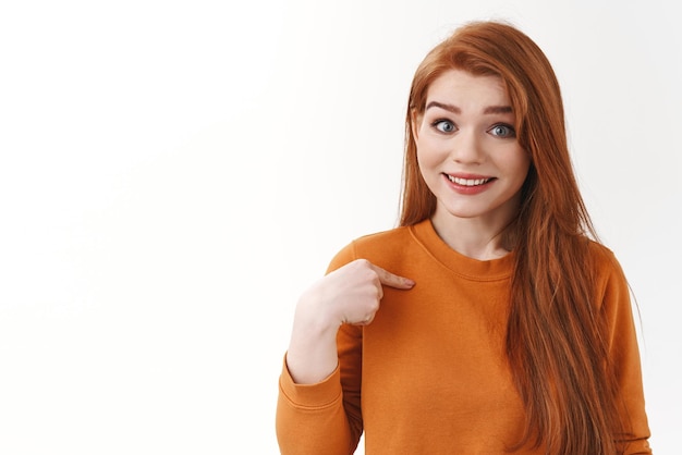 Surprised cute modest redhead girl asking you talking to me pointing herself and smiling hopeful want being picked asking permission participate volunteering offer own help Copy space