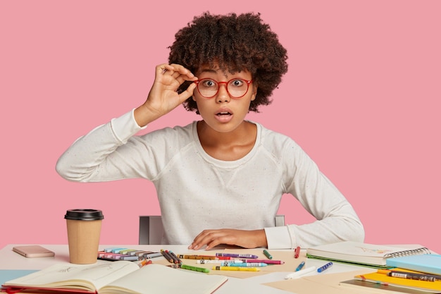 Surprised designer keeps hands on rim of spectacles