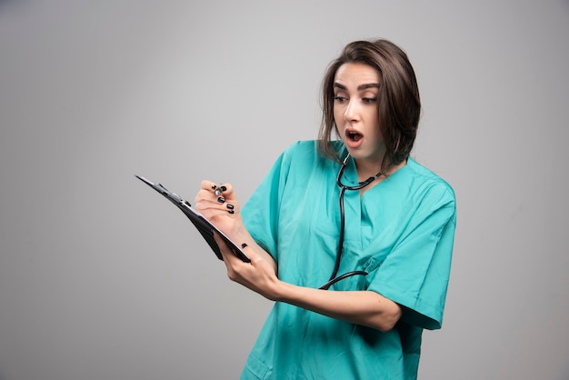 Surprised doctor in blue uniform standing on gray background. High quality photo