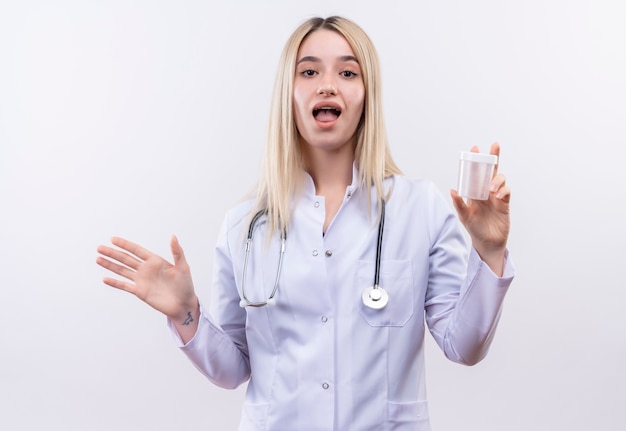 청진 기 및 격리 된 흰색 배경에 빈 캔을 들고 의료 가운을 입고 놀된 의사 젊은 금발 소녀