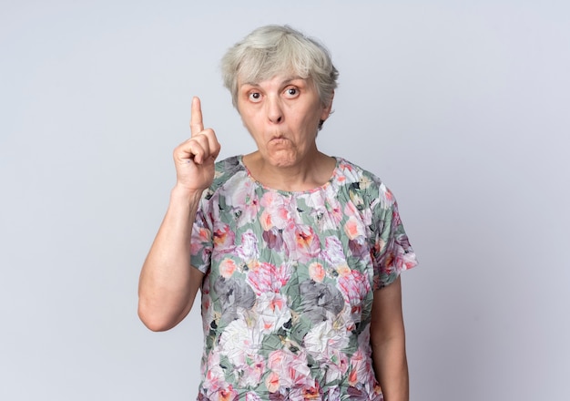 Free photo surprised elderly woman points up isolated on white wall