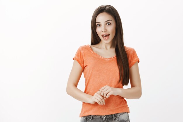 Surprised and enthusiastic brunette girl gasping, looking amazed, hear interesting news, promo discount