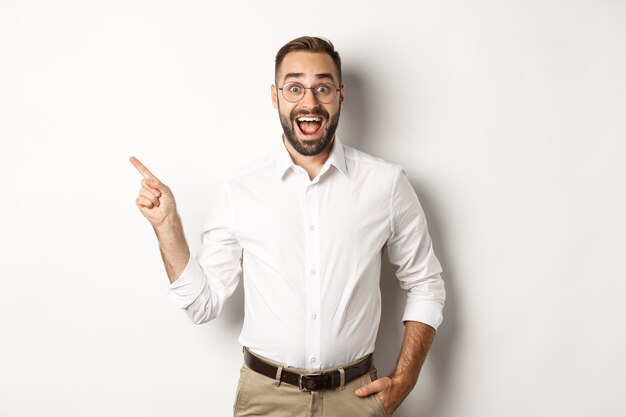 Surprised and excited man making announcement. Businessman pointing finger left