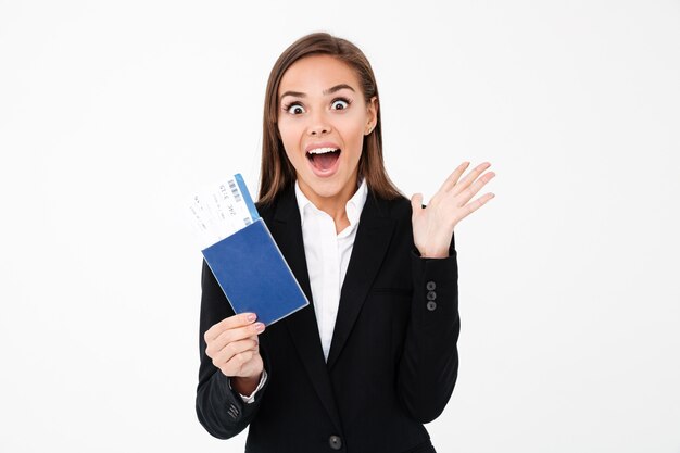 Удивленная взволнованная симпатичная деловая женщина держит билеты и паспорт