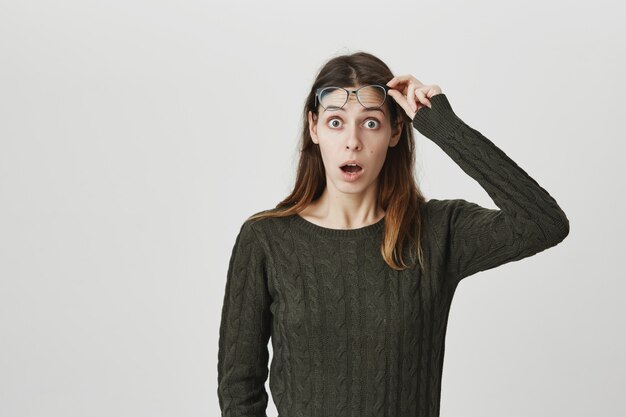 Surprised and excited, shocked woman take-off glasses and stare with dropped jaw