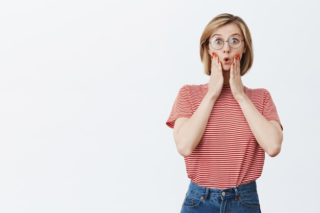 Surprised and excited woman in glasses looking at great offer, stare amazed