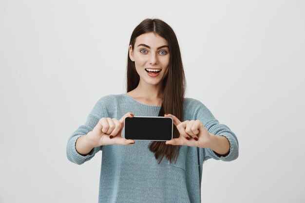 Surprised excited woman showing smartphone display