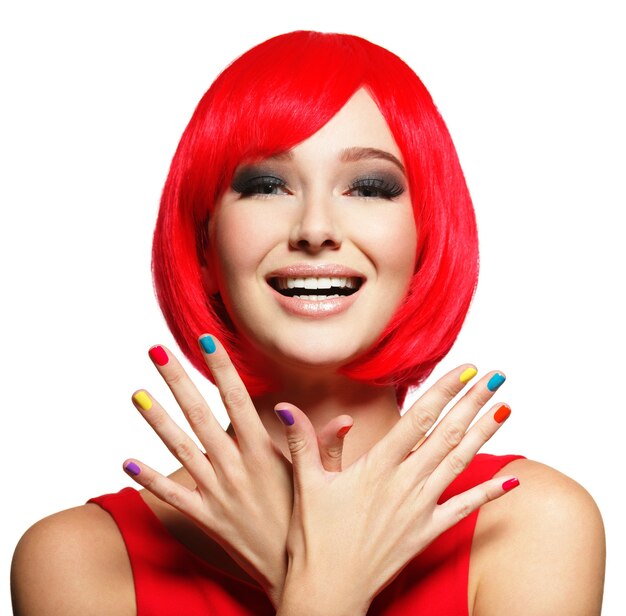 Surprised face of an young pretty woman with bright red hairs and multicolor nails.